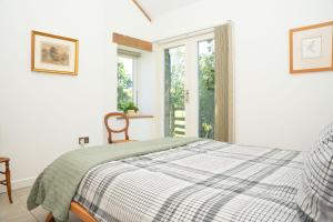 a white bedroom with a bed and a window at Cosy Rural Barn with Private Garden & Forest - The Cart Barn in Tavistock