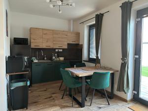 a kitchen with a table and green chairs at apartman Losonci in Nesvady