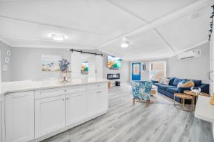 a kitchen and living room with white cabinets and a blue couch at Dolphin House Rental Vacation in Fort Myers Beach