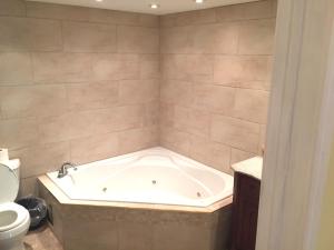 a bath tub in a bathroom with a toilet at Grey Rose Suites in Hanover