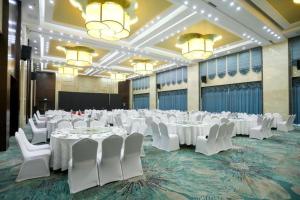 a large banquet hall with white tables and white chairs at Hundred Hotel Qingdao in Qingdao
