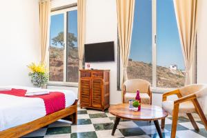 a bedroom with a bed and a tv and a table at ALBA Mountain Villa's in Chirwa