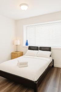 ein weißes Schlafzimmer mit einem großen Bett und einem Fenster in der Unterkunft Sweet 2-bedrooms house in Vancouver in Vancouver