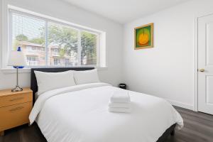 ein weißes Schlafzimmer mit einem weißen Bett und einem Fenster in der Unterkunft Sweet 2-bedrooms house in Vancouver in Vancouver