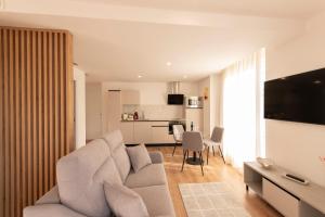 ein Wohnzimmer mit einer weißen Couch und einer Küche in der Unterkunft ALAIA ROOMS, Apartamentos Turísticos 0003 in Logroño