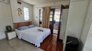 a bedroom with a bed with white sheets and blue pillows at Cozy Studio Apt Pool Free WIFI in Suva +23 photos