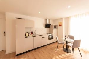 eine Küche mit weißen Schränken und einem Tisch und Stühlen in der Unterkunft ALAIA ROOMS, Apartamentos Turísticos 0003 in Logroño