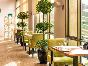 um restaurante com mesas e cadeiras e vasos de árvores em Sofitel Saigon Plaza em Cidade de Ho Chi Minh