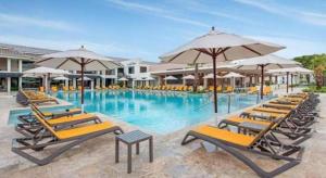 a large swimming pool with chairs and umbrellas at Celuisma Playa Dorada All Inclusive in Sampiño