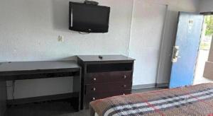1 dormitorio con tocador y TV en la pared en Scottish Inns Augusta, en Augusta