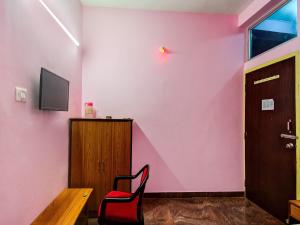 a room with a pink wall with a chair and a door at Hotel O Kolkata Palace in Puri +46 photos