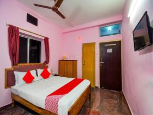 a bedroom with a bed with red pillows and a tv at Hotel O Kolkata Palace in Puri
