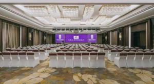 YuyaoにあるExcemon Yuyao Hemudu Hotelの椅子が並び、紫色のスクリーンがある宴会場