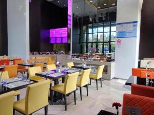 a dining room with tables and yellow chairs at Holiday Villa Hotel & Residence Shanghai Jiading in Xuhang