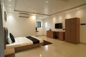 ein Schlafzimmer mit einem Bett, einem Schrank und einem TV in der Unterkunft Coral Sand Beach Resort By Privy Stays in Nagaon