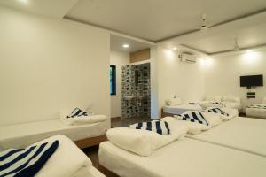 ein Zimmer mit vier weißen Betten und einem Fernseher in der Unterkunft Coral Sand Beach Resort By Privy Stays in Nagaon + 28 Fotos