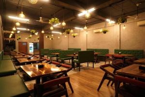 ein Restaurant mit Holztischen und grünen Stühlen in der Unterkunft Coral Sand Beach Resort By Privy Stays in Nagaon