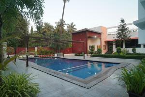 ein Schwimmbad vor einem Gebäude in der Unterkunft Coral Sand Beach Resort By Privy Stays in Nagaon