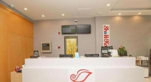 a lobby with a white counter and a tv on the wall at Shell Shanghai Jiading Nanxiang Town Minzhu Street Hotel in Fengbang