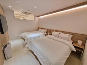 a hotel room with two beds and a flat screen tv at 인별호텔 in Suncheon
