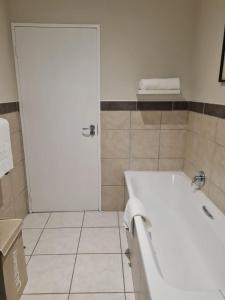 a bathroom with a white tub and a white door at 1 Bedroom Luxury Apartment, Beacon Bay North, East London in East London