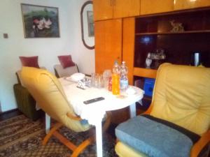 a table with two yellow chairs and a white table with at Kulcsosház vendégház in Hollóháza +6 photos