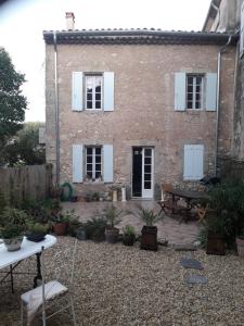 a brick house with a table and chairs in front of it at Maison Rose - Maison de village avec jardin privé, centre Capestang in Capestang