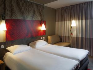 a hotel room with two beds and a chair at ibis Paris La Defense Courbevoie in Courbevoie