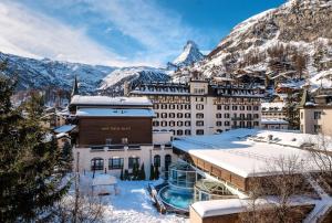 a hotel in the snow with a mountain in the background at Mont Cervin Palace in Zermatt