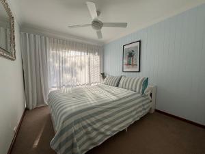 een bed in een slaapkamer met een plafondventilator bij Catalina Cove-From Door to Shore in 2 Minutes in Shoal Bay