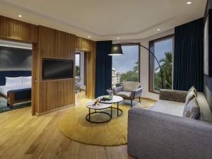a living room with a couch and a tv and a bed at Novotel Mumbai Juhu Beach in Mumbai