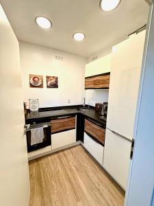 a kitchen with white cabinets and a wooden floor at Porschenahe Wohung in Stuttgart
