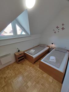 une chambre mansardée avec deux lits et une fenêtre dans l'établissement Apartment by MICHELLE, à Čatež ob Savi