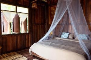 une chambre avec un lit avec moustiquaire dans l'établissement Hidden for Rest, à Ban Huai Khai