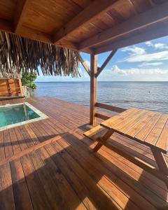 a wooden deck with a table and a swimming pool at Fare Vai Uteute in Uturoa