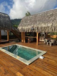 a swimming pool on a wooden deck with a hut at Fare Vai Uteute in Uturoa