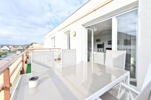 a glass balcony with white furniture on a white house at L'équinox in Bourgheim