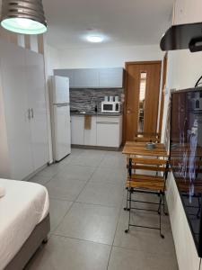 a kitchen with white appliances and a table and a chair at מגדל חי 1 in Eilat