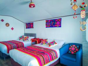 a bedroom with two beds and a blue chair at Sol del Titikaka Lodge in Puno