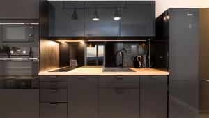a kitchen with black cabinets and a stainless steel refrigerator at Maya's Flats & Resorts 26 - Panorama View in Gdańsk
