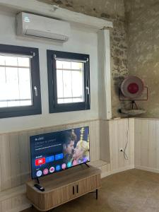 a flat screen tv in a room with two windows at Maison loft au cachet ancien in Villasavary +15 photos