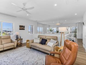 Una sala de estar con un sofá y sillas y una cocina. en High Tide 4BR 3 level house Ocean views & Pool, en Kingscliff