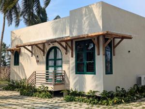 a small white house with a porch and a balcony at LAWA Bintan Berakit Village Cottage in Berakit