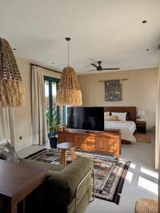 a living room with a bed and a television at LAWA Bintan Berakit Village Cottage in Berakit