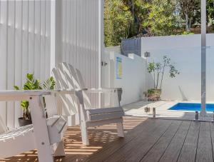 un patio con 2 sillas, una mesa y una piscina en High Tide 4BR 3 level house Ocean views & Pool, en Kingscliff