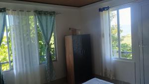 a bedroom with two windows with white curtains and a bed at Sayatri stay in Karsiyang