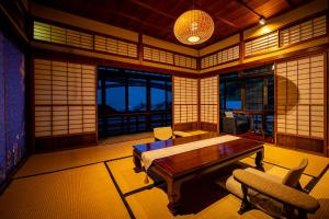 a room with a table and a chair and windows at Okamotoya in Beppu