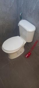 a white toilet in a bathroom with a red tool at Dumaguete Divers in Dauin