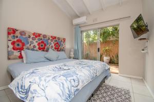 ダーバンにあるNo 20 On the Beach Guesthouseのベッドルーム1室(花柄のヘッドボードと窓付)