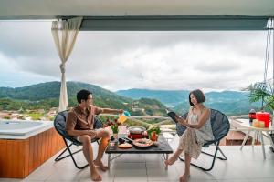 a man and woman sitting around a table on a balcony at ม่อนล้านวิว ม่อนแจ่ม in Ban Pong Khai Tai
